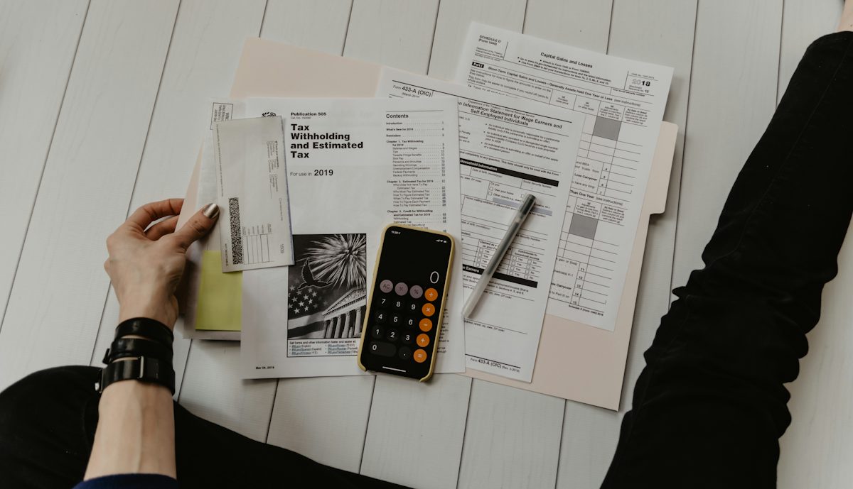 person holding paper near pen and calculator — illustrative stock photo
