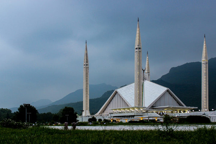 The Faisal Mosque with four tall minarets against a backdrop of mountains in Islamabad — illustrative stock photo